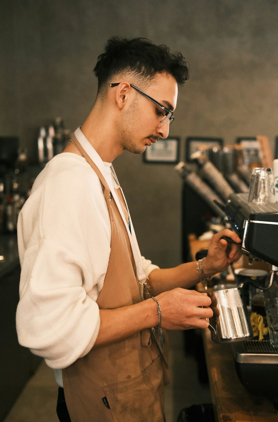 Barista steaming milk behind a coffee shop counter